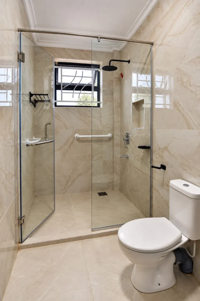 Glass shower enclosure and close-coupled toilet in a renovated Kilimambogo bathroom