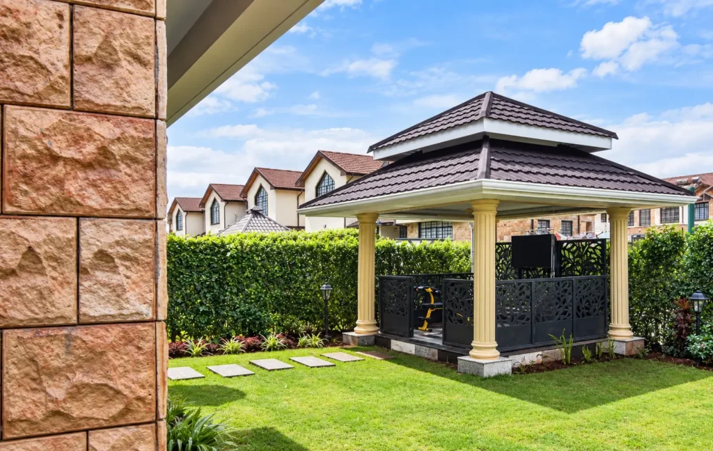 Outdoor gym gazebo in a garden in Edenville, Kiambu, with a tiled two-tier roof, cream columns and black laser-cut screens